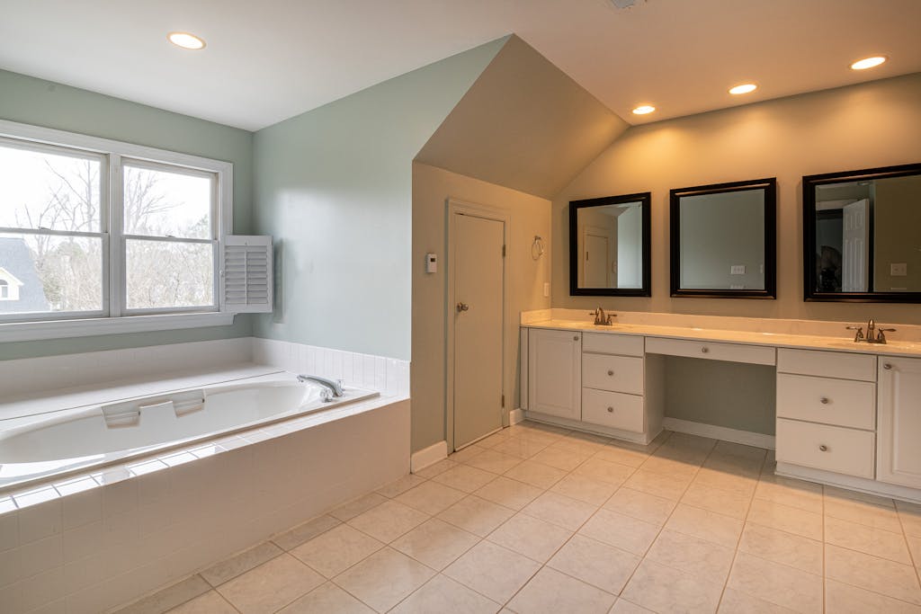 A bright and spacious bathroom with a luxury bathtub and dual sink vanity, ideal for contemporary home interiors.